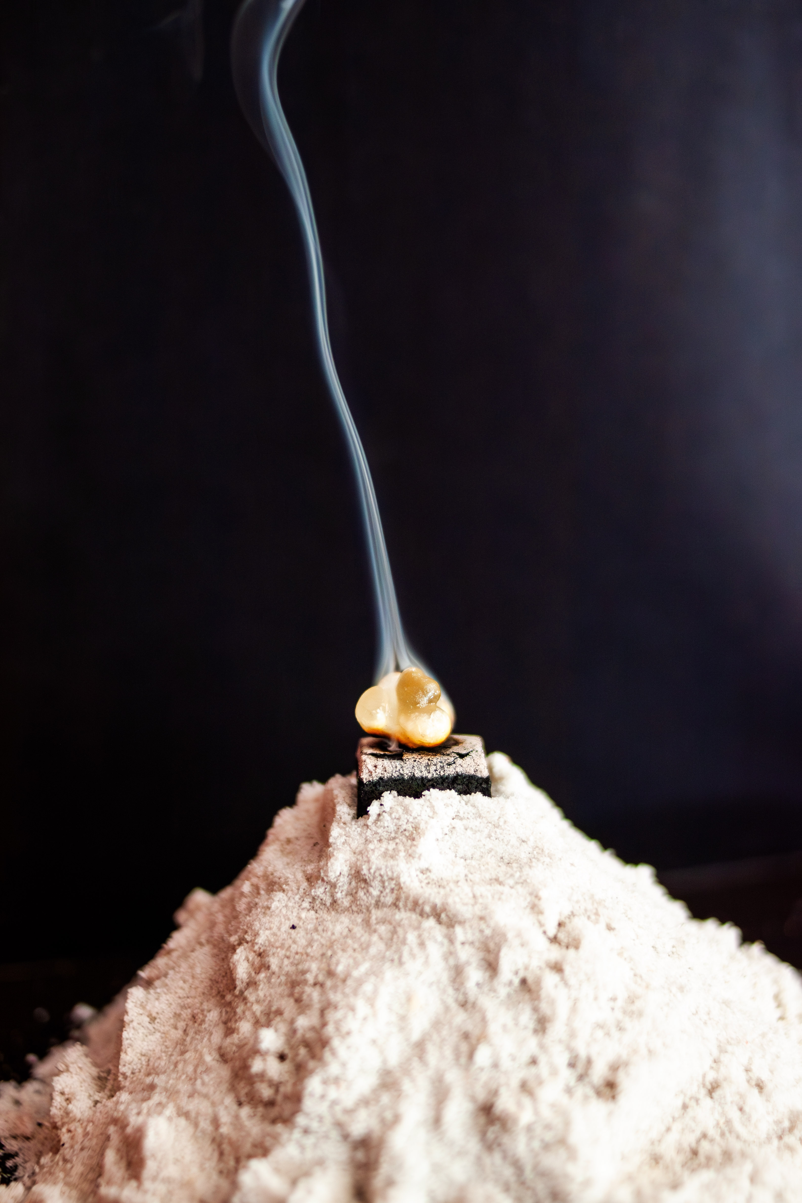 Frankincense resin burning on charcoal with smoke rising